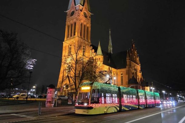 Świąteczny tramwaj w nocy na tle kościoła