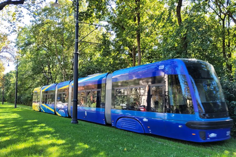Żółto-niebieski tramwaj na zielonym torowisku