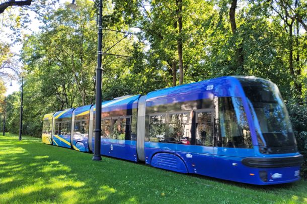 Żółto-niebieski tramwaj na zielonym torowisku